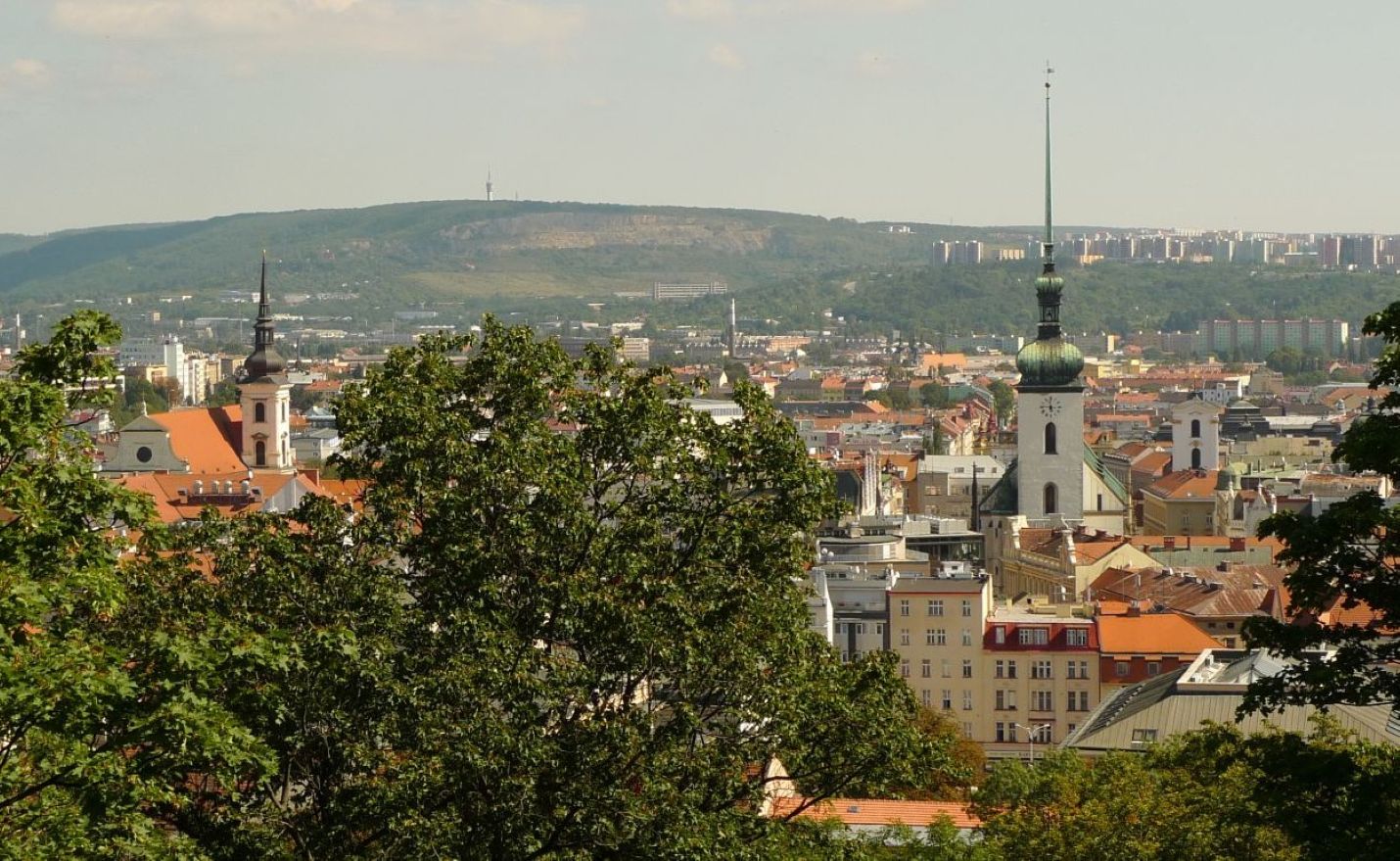 Historické Brno s kostely sv. Tomáše a sv. Jakuba z pevnosti Špilberk, v pozadí nejvýznamnější energetické místo města na Hádech